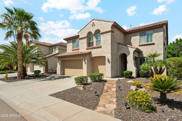 mediterranean / spanish-style house with a garage, stucco siding, driveway, and a tile roof