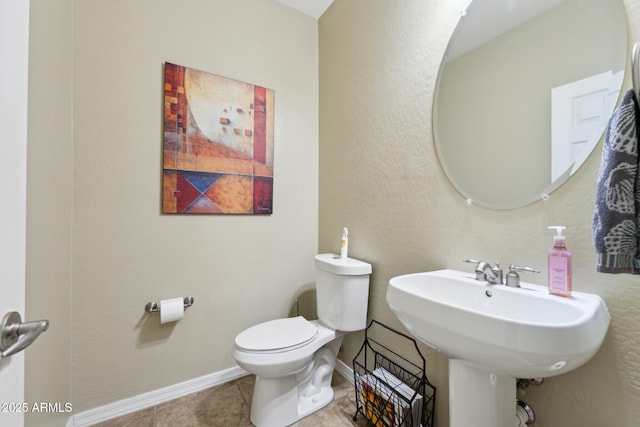 half bathroom featuring toilet, baseboards, a sink, and tile patterned flooring