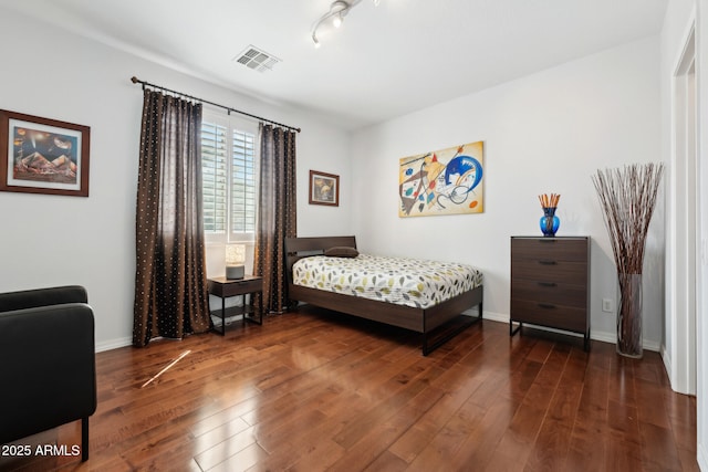 bedroom with baseboards, visible vents, and hardwood / wood-style floors
