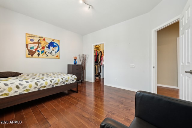 bedroom featuring a closet, baseboards, a walk in closet, and wood finished floors