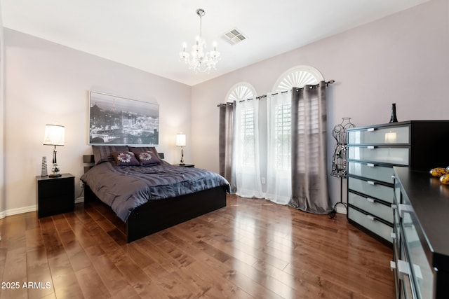 bedroom featuring visible vents, baseboards, wood finished floors, and a chandelier