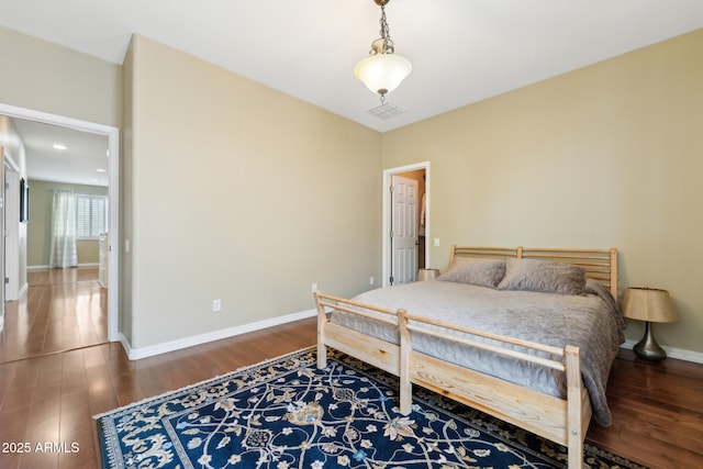 bedroom featuring baseboards, wood finished floors, and visible vents