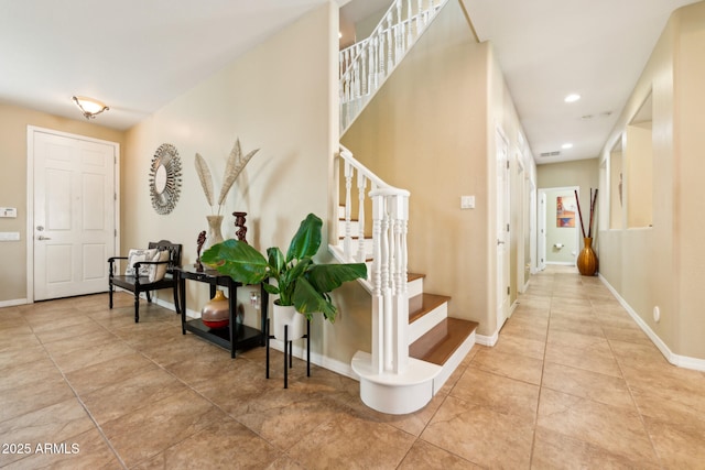 foyer with stairway, baseboards, tile patterned flooring, and visible vents