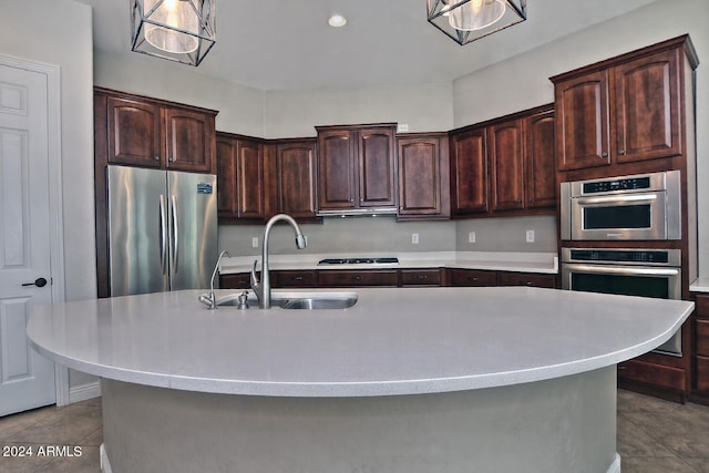 kitchen featuring a center island with sink, stainless steel appliances, dark brown cabinetry, and sink