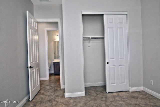 unfurnished bedroom with a closet and dark tile floors