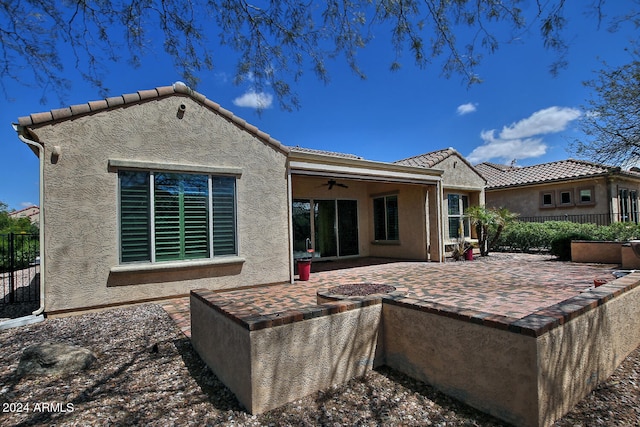 rear view of property with ceiling fan and a patio area