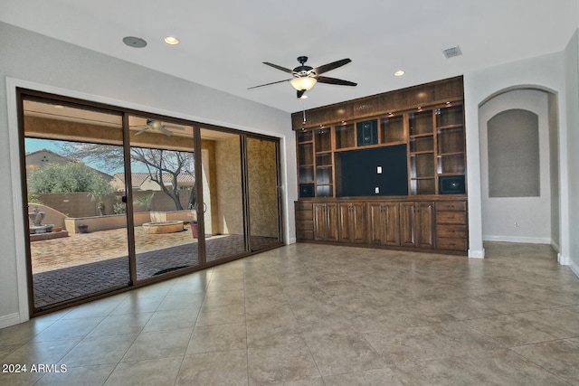 unfurnished living room with ceiling fan, built in shelves, and light tile floors