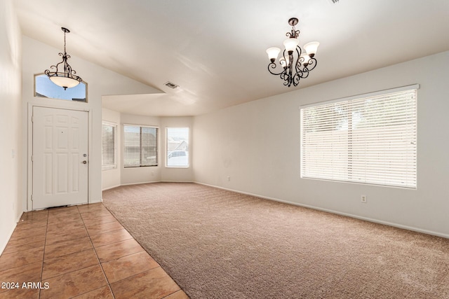 tiled foyer with lofted ceiling and a notable chandelier