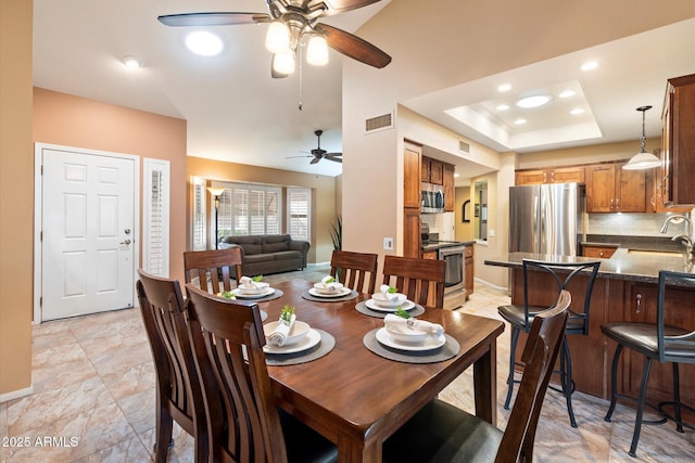 dining room featuring sink and a tray ceiling