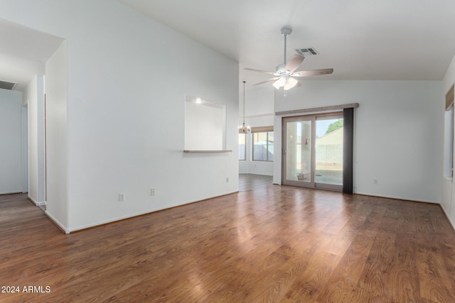 unfurnished living room with dark hardwood / wood-style flooring, ceiling fan with notable chandelier, and vaulted ceiling