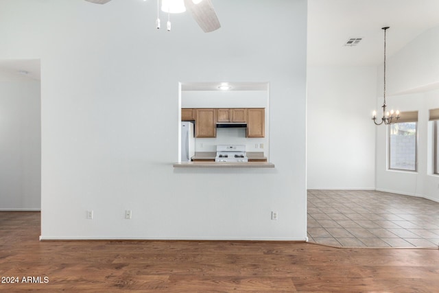 unfurnished living room with hardwood / wood-style floors and ceiling fan with notable chandelier