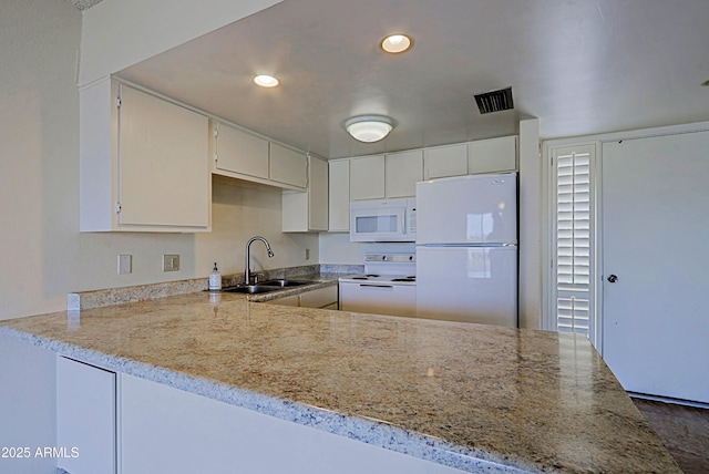 kitchen with white appliances, visible vents, a peninsula, a sink, and recessed lighting