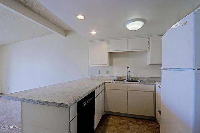 kitchen with a peninsula, a sink, black dishwasher, light countertops, and freestanding refrigerator