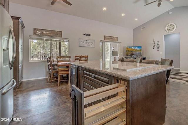 kitchen with lofted ceiling, stainless steel refrigerator with ice dispenser, dark brown cabinetry, and a center island