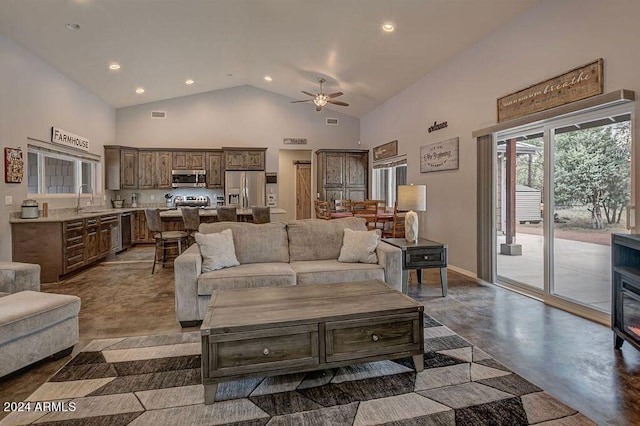 living room featuring concrete floors, sink, high vaulted ceiling, and ceiling fan