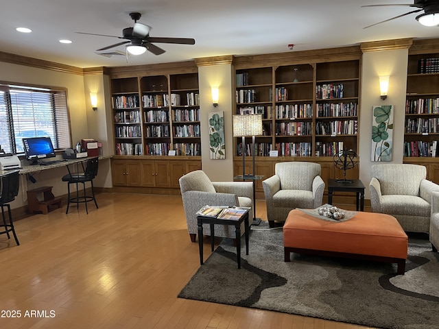 living area featuring crown molding, light hardwood / wood-style flooring, and ceiling fan