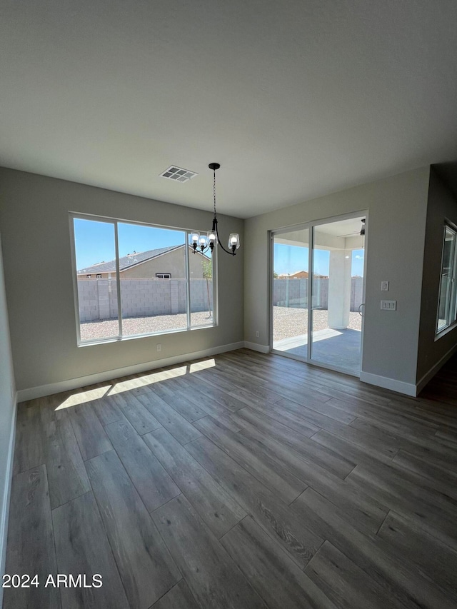 unfurnished dining area with a chandelier and dark hardwood / wood-style floors