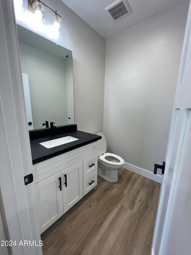 bathroom featuring vanity, toilet, and hardwood / wood-style floors