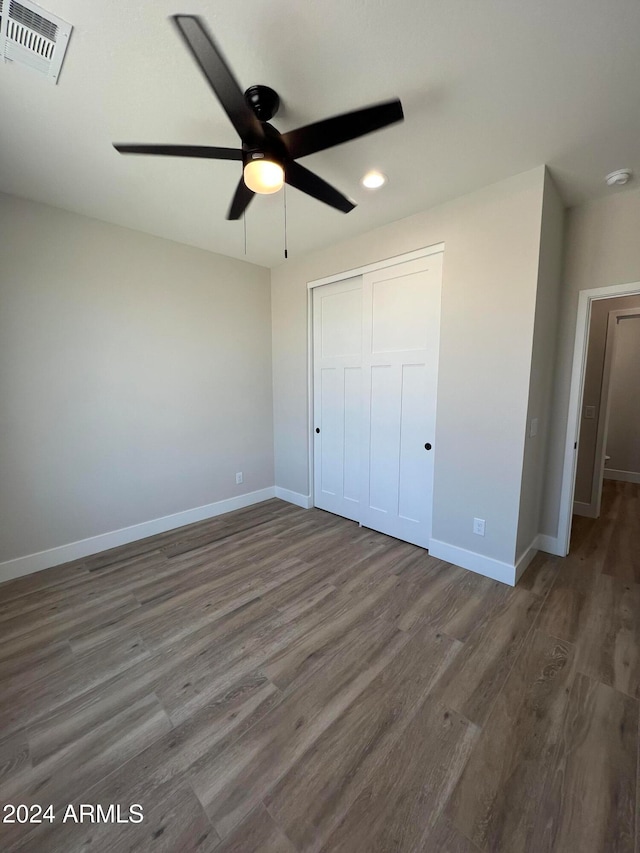 unfurnished bedroom with a closet, dark hardwood / wood-style floors, and ceiling fan