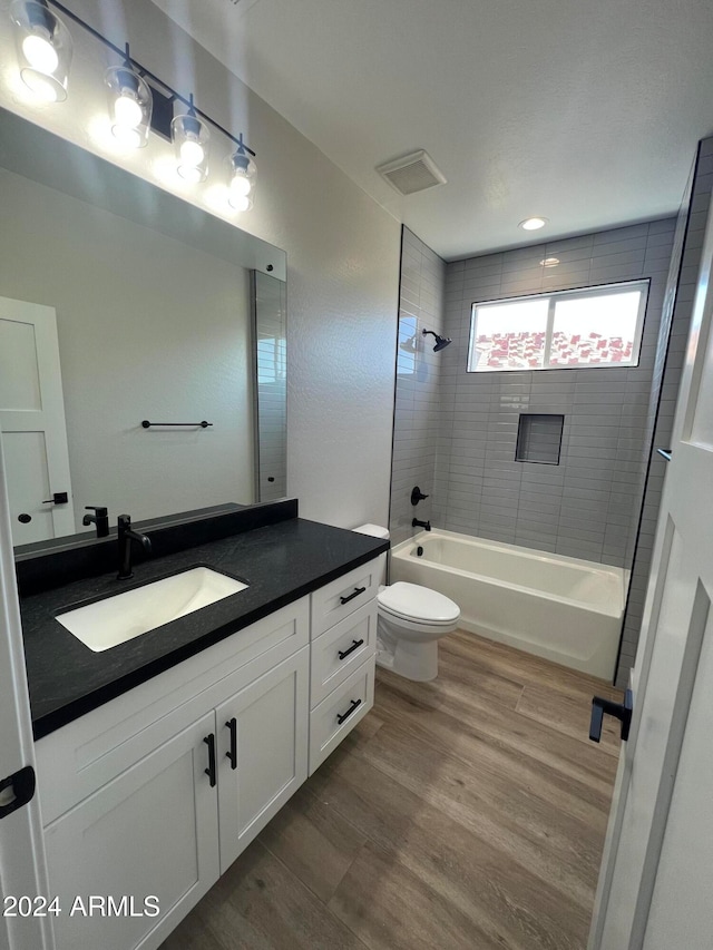 full bathroom with vanity, toilet, hardwood / wood-style floors, and tiled shower / bath