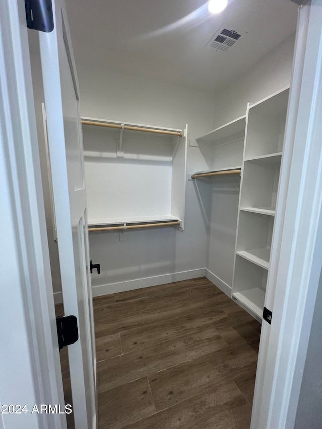 walk in closet with dark hardwood / wood-style floors