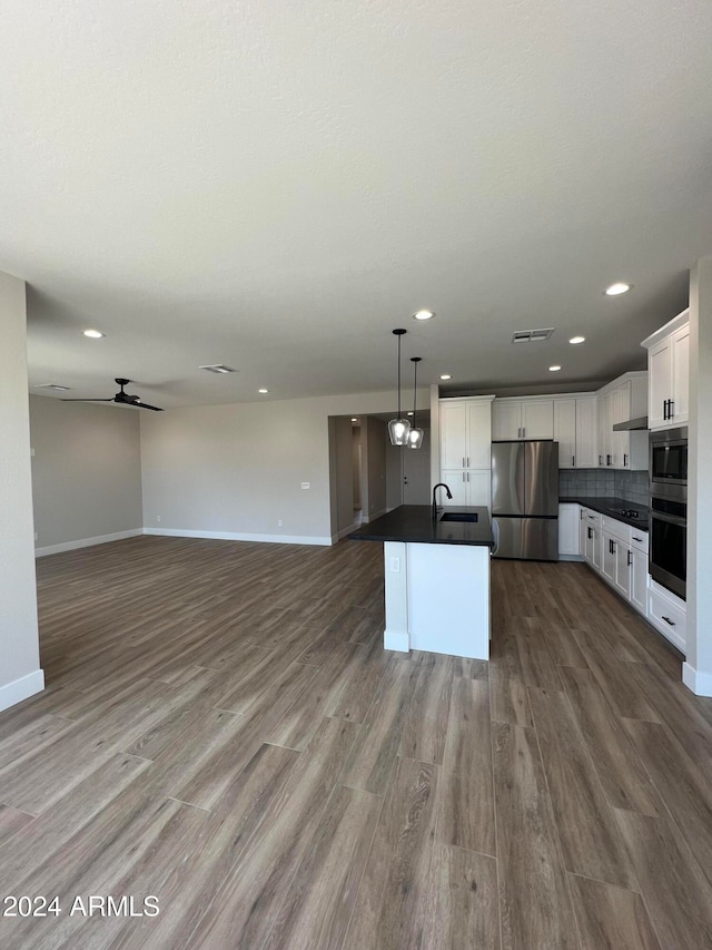 kitchen with stainless steel appliances, pendant lighting, white cabinets, light hardwood / wood-style flooring, and a center island with sink