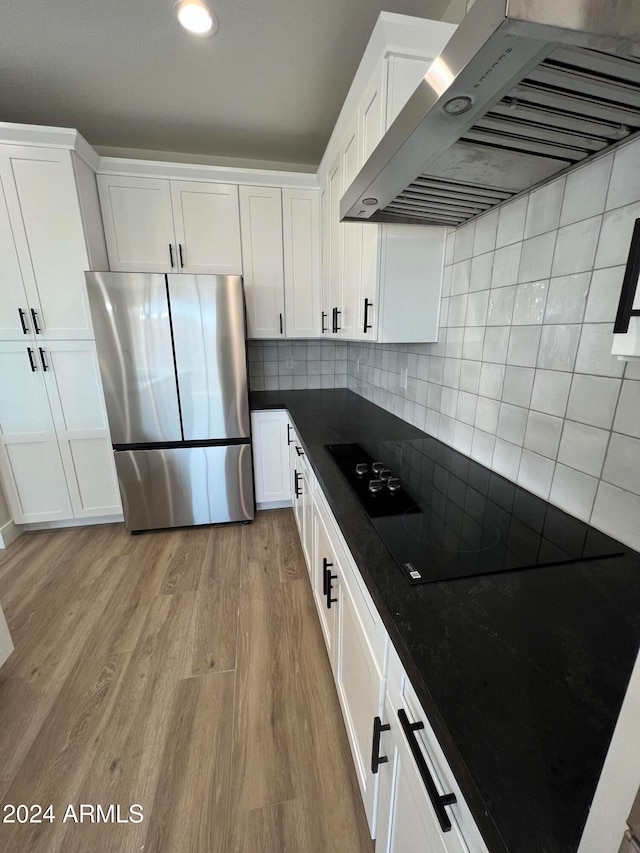 kitchen with white cabinetry, wall chimney exhaust hood, and stainless steel refrigerator