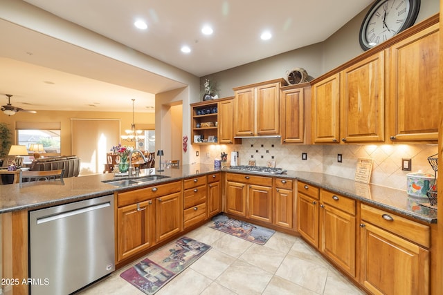 kitchen with appliances with stainless steel finishes, ceiling fan with notable chandelier, pendant lighting, tasteful backsplash, and sink