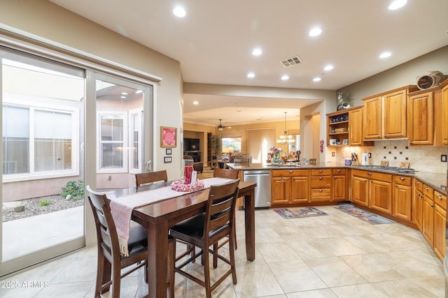 kitchen with pendant lighting, sink, tasteful backsplash, stainless steel dishwasher, and kitchen peninsula