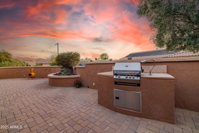 patio terrace at dusk featuring area for grilling