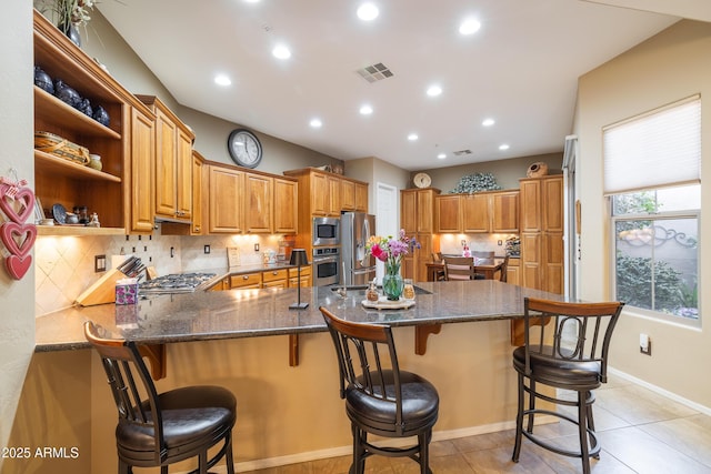 kitchen with stainless steel appliances, a breakfast bar, kitchen peninsula, and decorative backsplash