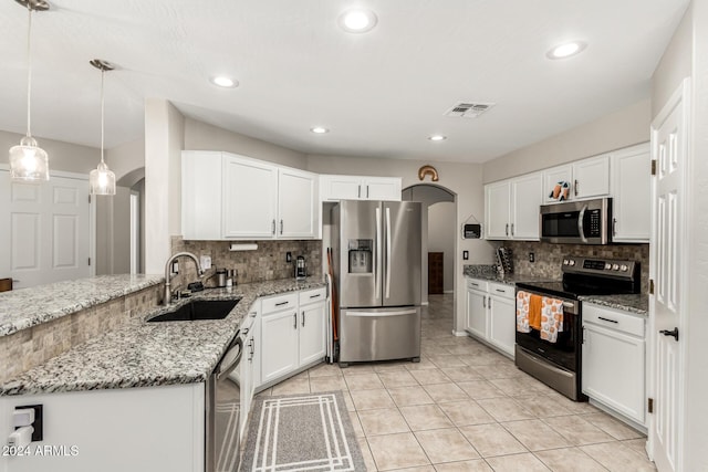 kitchen featuring appliances with stainless steel finishes, light stone counters, sink, pendant lighting, and white cabinets