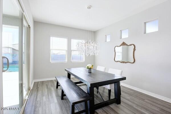 dining space featuring a notable chandelier, baseboards, and wood finished floors