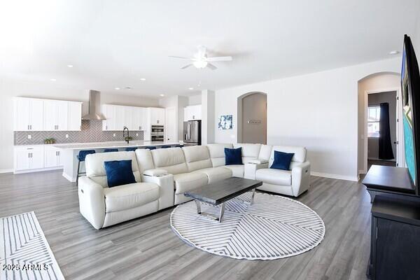 living area featuring baseboards, arched walkways, and light wood-style floors