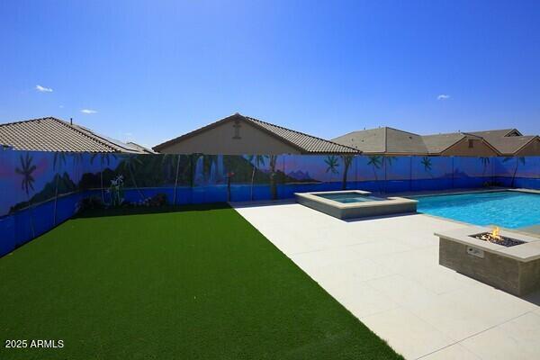 view of swimming pool featuring a patio area, a pool with connected hot tub, a fenced backyard, and an outdoor fire pit