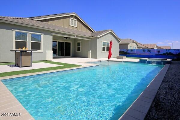 back of property featuring stucco siding, a pool with connected hot tub, a patio, fence, and ceiling fan