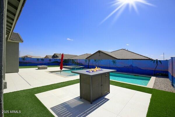 view of swimming pool with a patio area, a fenced backyard, a pool with connected hot tub, and a fire pit