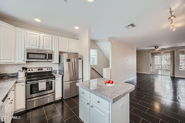 kitchen featuring visible vents, a kitchen island, open floor plan, appliances with stainless steel finishes, and ceiling fan