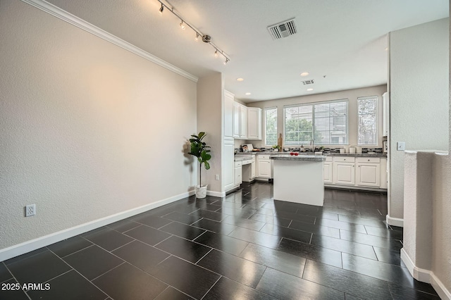 kitchen featuring visible vents, track lighting, a kitchen island, white cabinetry, and baseboards