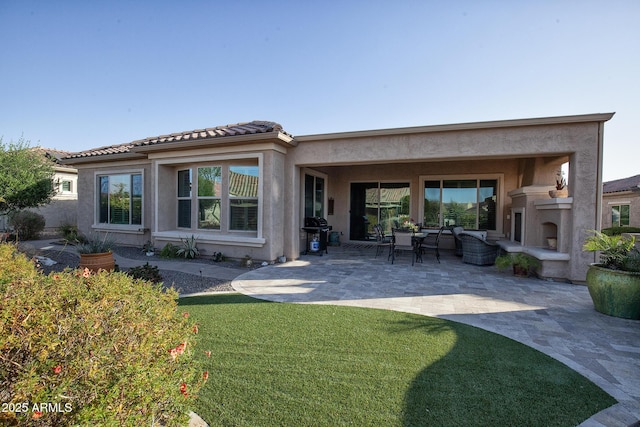 back of house with a lawn, a patio area, and an outdoor fireplace