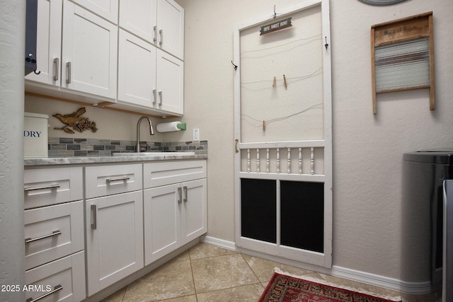 clothes washing area featuring light tile patterned floors and sink