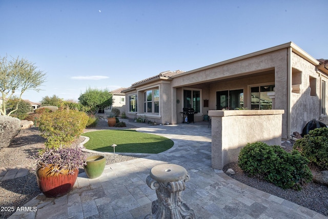 rear view of house featuring a lawn and a patio