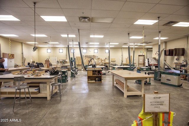 misc room with a workshop area, concrete floors, and a paneled ceiling