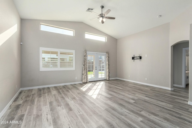 spare room featuring a high ceiling, light wood-type flooring, ceiling fan, and french doors