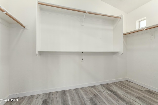 walk in closet with light hardwood / wood-style floors and vaulted ceiling