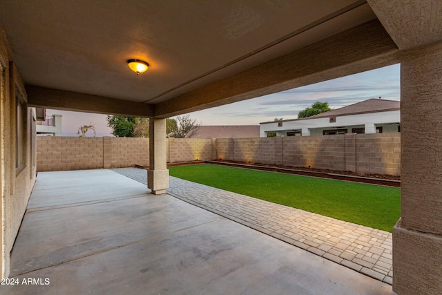 patio terrace at dusk featuring a lawn