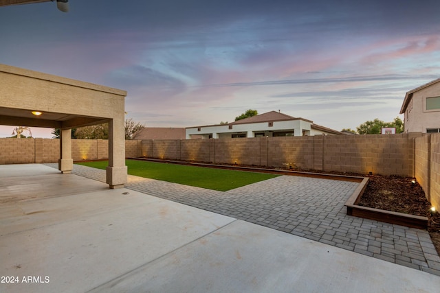 patio terrace at dusk featuring a yard