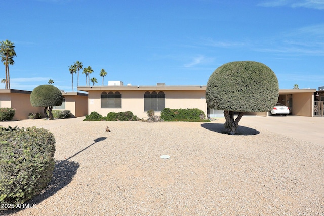 view of front facade with an attached carport, driveway, and stucco siding