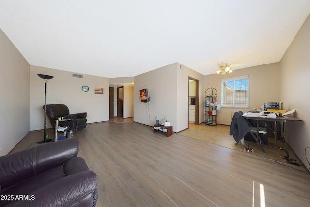 living area with wood finished floors, visible vents, and an inviting chandelier