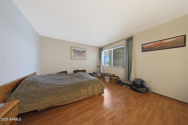 bedroom with a textured ceiling and wood finished floors